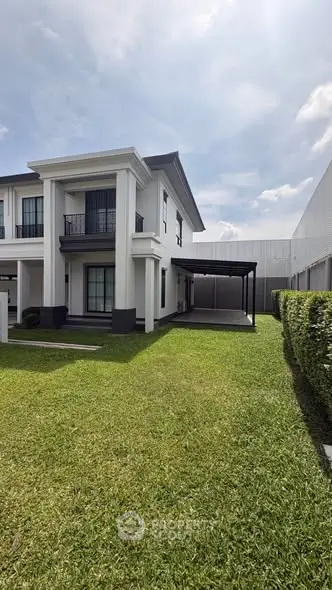 Elegant two-story house with manicured lawn and carport, showcasing modern architectural design.