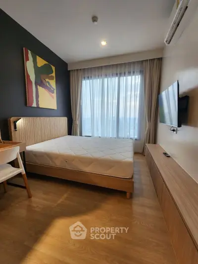 Modern bedroom with large window and stylish decor in a contemporary apartment.