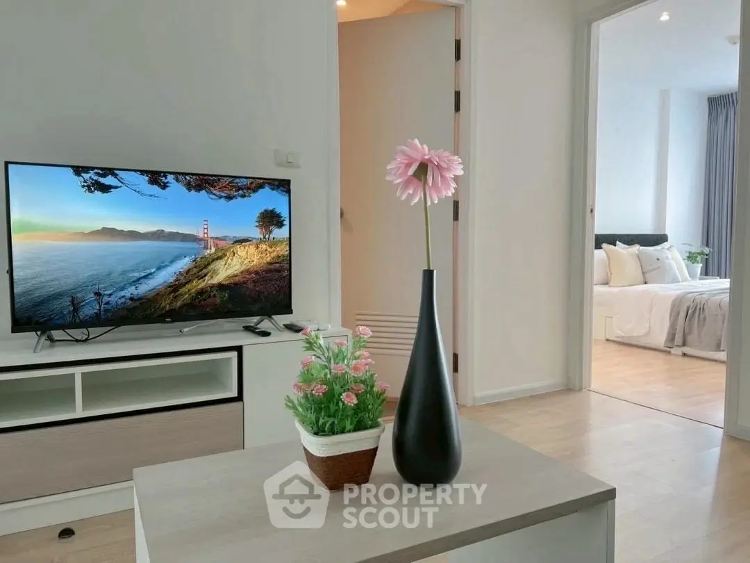 Modern living room with TV and view into cozy bedroom