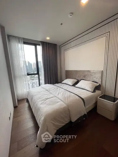 Modern bedroom with city view, featuring elegant decor and cozy bedding in a high-rise apartment.