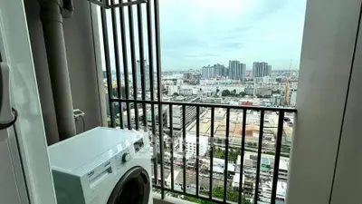 High-rise apartment balcony with washing machine and stunning city view.