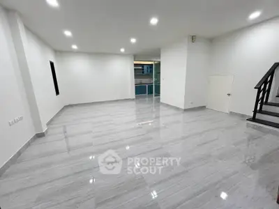 Spacious modern living room with sleek flooring and staircase, ideal for contemporary living.