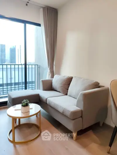 Modern living room with cozy gray sofa and city view balcony in a stylish apartment.