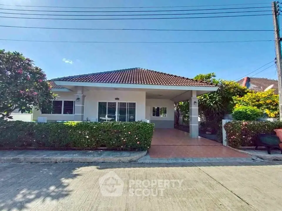 Charming single-story house with tiled roof and lush garden in serene neighborhood.