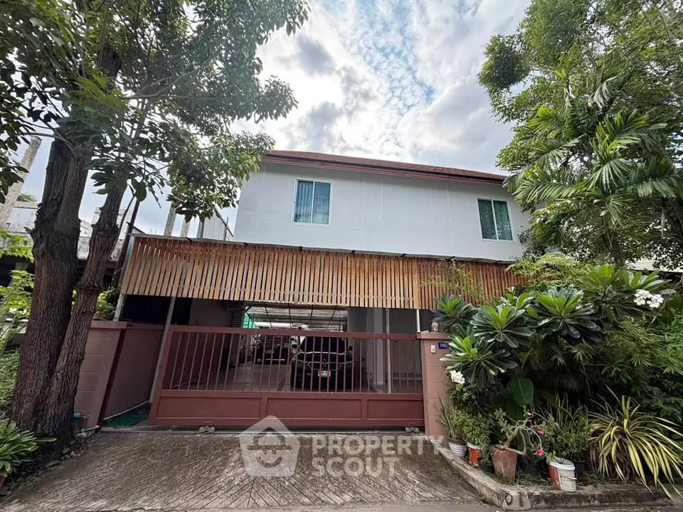 Charming two-story house with lush garden and gated entrance, perfect for family living in a serene neighborhood.