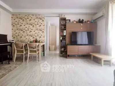 Spacious living room with modern decor and natural light, featuring a stylish entertainment center and dining area.
