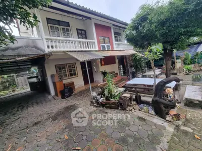 Charming two-story house with lush garden and outdoor seating area, perfect for family gatherings.