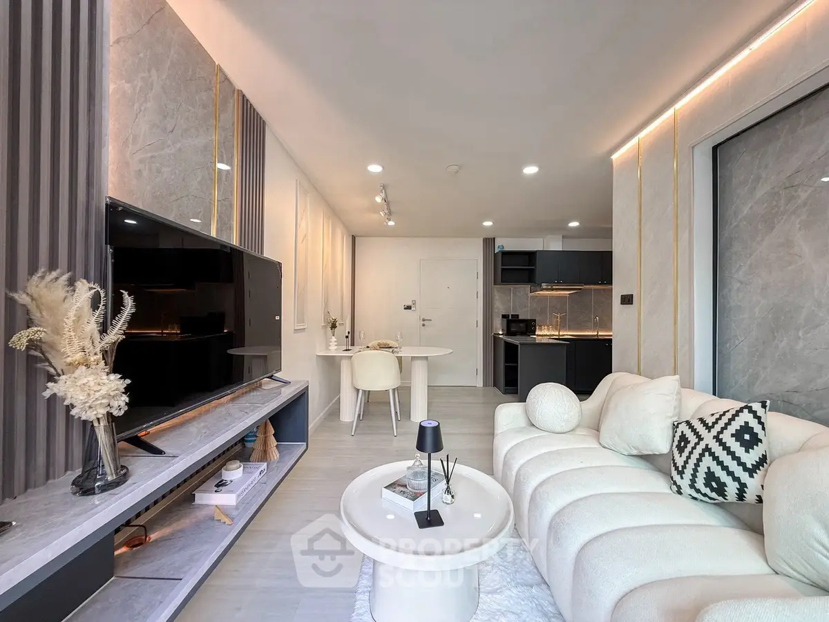 Modern living room with elegant decor and open kitchen layout, featuring stylish furniture and ambient lighting.