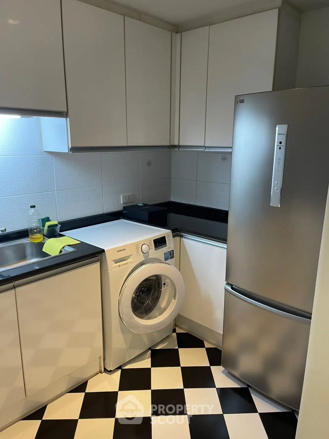 Modern kitchen with sleek appliances and stylish black-and-white checkered flooring.