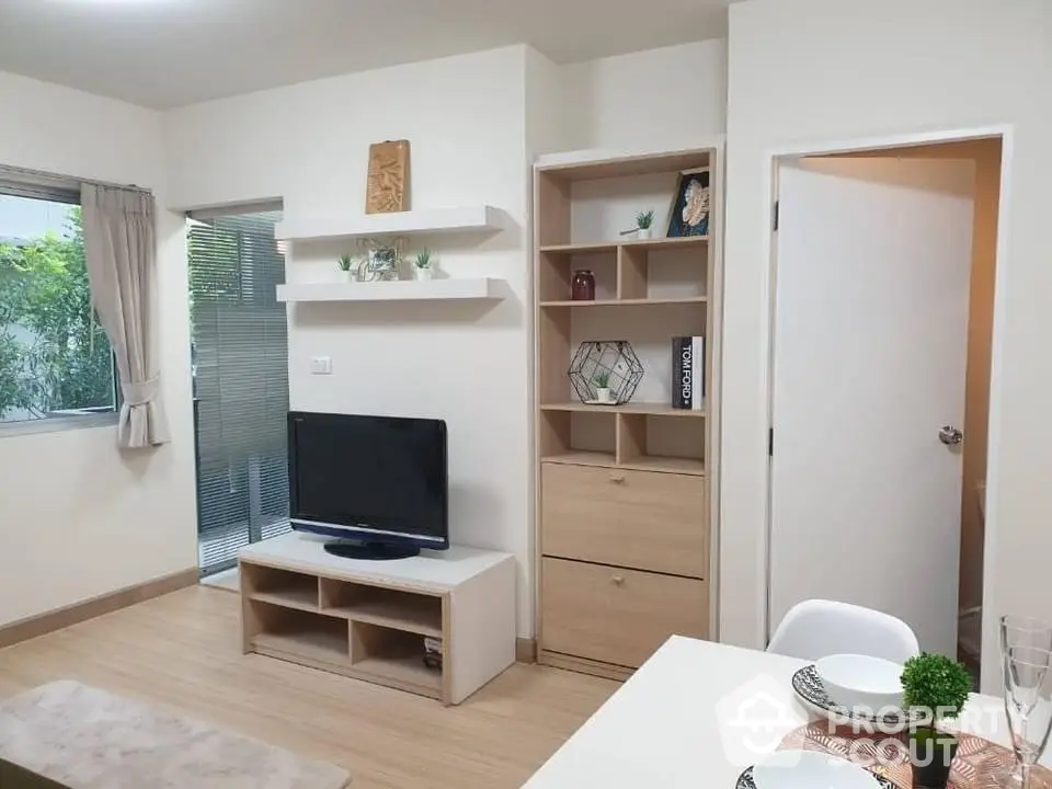 Modern living room with TV, shelves, and dining area in cozy apartment