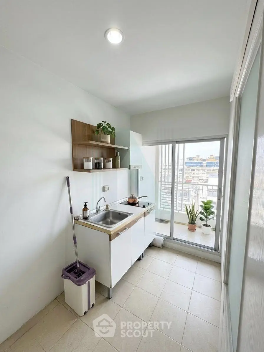 Bright kitchen with balcony access and modern sink setup in a high-rise apartment.