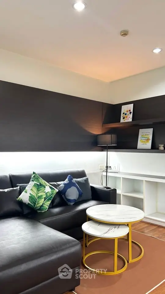 Modern living room with stylish black sofa, decorative pillows, and nested coffee tables in a cozy setting.