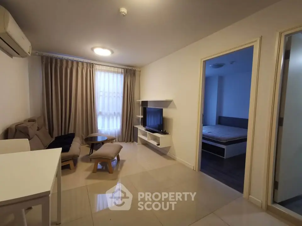 Modern living room with sleek furniture and open layout, adjacent to a cozy bedroom.