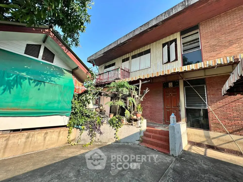 Charming two-story brick house with lush greenery and spacious outdoor area.