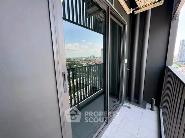 Modern balcony with glass doors offering stunning city views in a high-rise apartment.