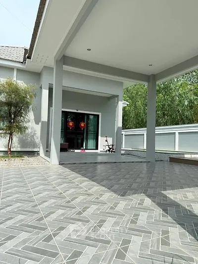 Spacious modern home with elegant tiled patio and lush greenery, perfect for outdoor relaxation.