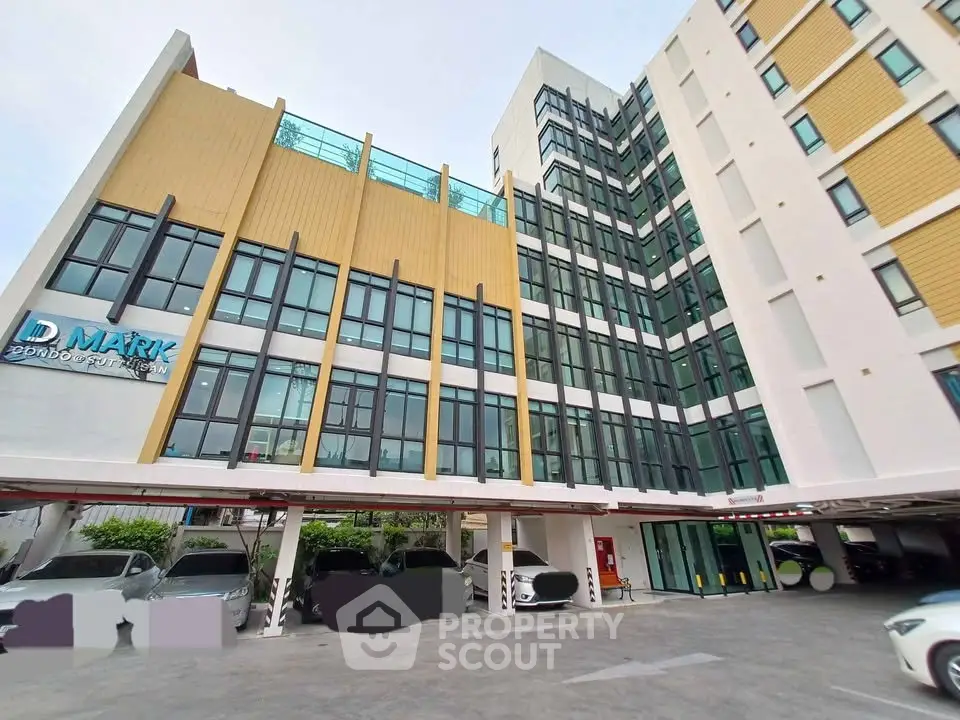 Modern multi-story building with parking area and sleek architectural design.