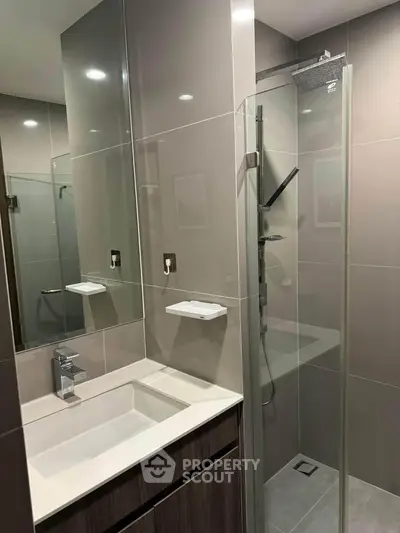 Modern bathroom with sleek shower and stylish vanity in contemporary apartment.