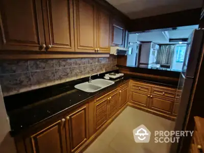 Spacious kitchen with wooden cabinets and modern appliances in a cozy apartment.