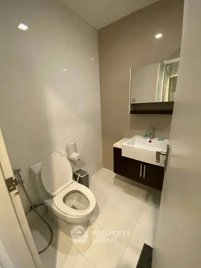 Modern bathroom with sleek fixtures and contemporary design, featuring a toilet and stylish vanity.
