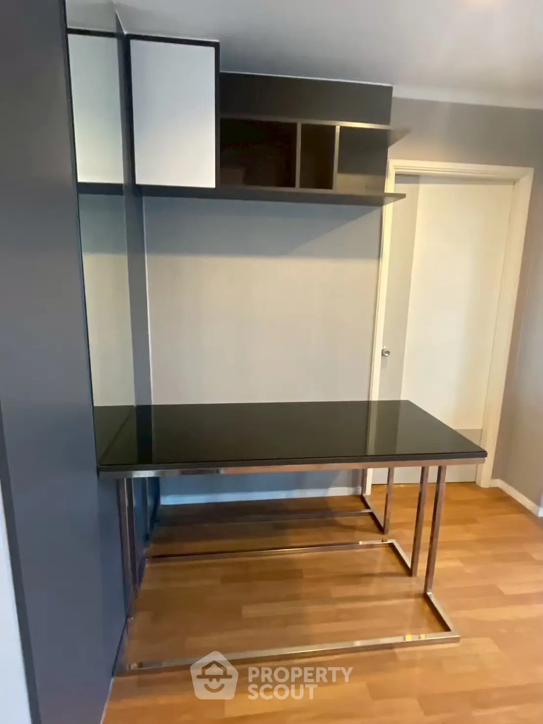 Modern study area with sleek black desk and shelving in contemporary apartment.