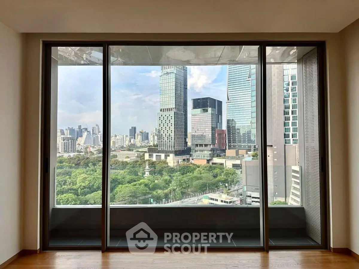 Stunning cityscape view from modern apartment window with lush greenery and skyscrapers.