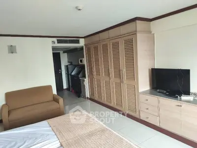 Spacious bedroom with built-in wardrobe and cozy seating area in modern apartment.
