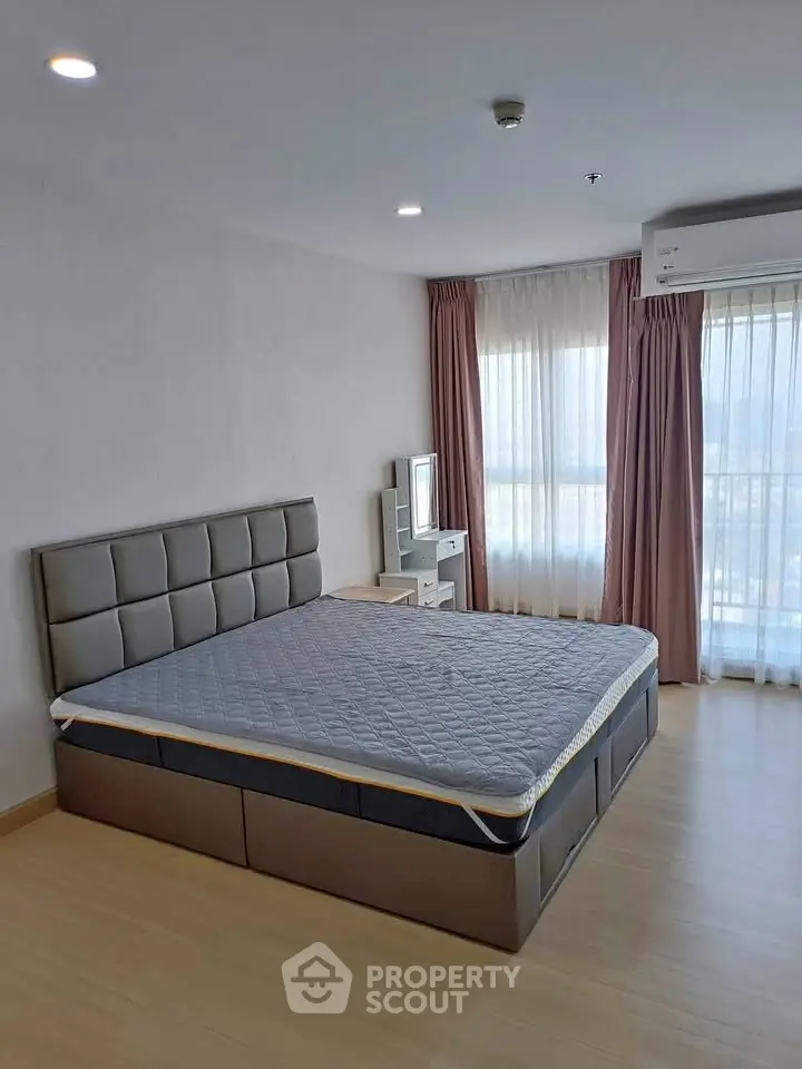 Spacious bedroom with modern bed and large windows offering natural light.