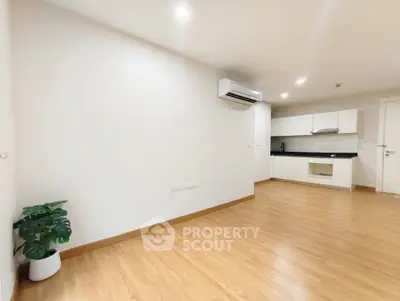 Spacious modern living room with wooden flooring and sleek kitchen area.
