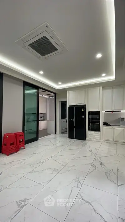 Spacious modern kitchen with sleek cabinetry and marble flooring, featuring built-in appliances and recessed lighting.