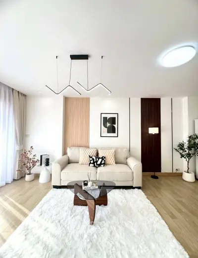 Modern living room with stylish decor, cozy white rug, and elegant lighting.