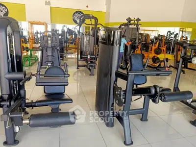 Spacious gym with modern fitness equipment and bright interior design.
