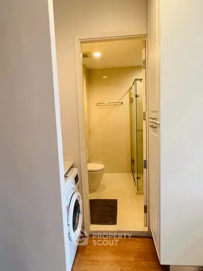 Compact bathroom with washing machine and glass shower enclosure