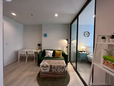 Modern living room with green sofa and glass partition to bedroom