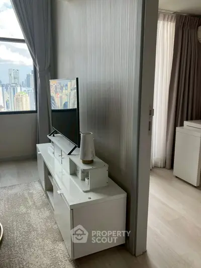 Modern living room with sleek TV stand and city view from window.