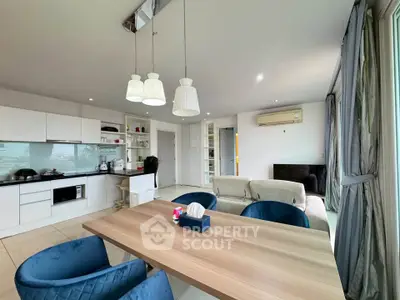 Spacious modern living room with open kitchen and elegant dining area, featuring stylish lighting and large windows.