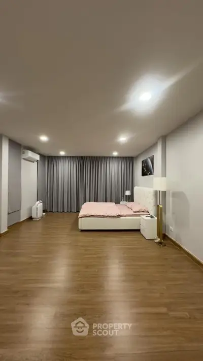 Spacious minimalist bedroom with wooden flooring and modern decor