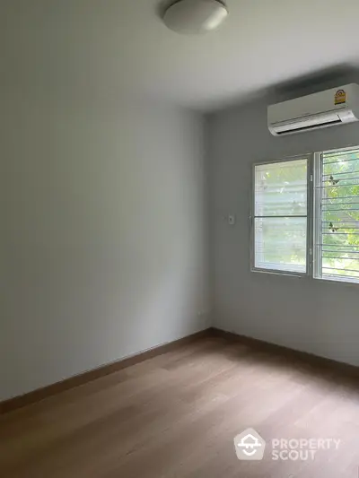 Spacious empty room with air conditioning and large window, perfect for customization.