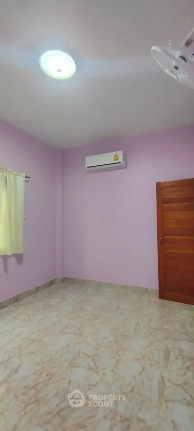 Spacious empty room with pink walls and air conditioning, ideal for customization.