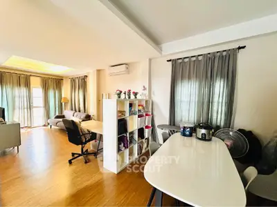 Spacious living room with modern decor and natural light, featuring a cozy seating area and dining space.