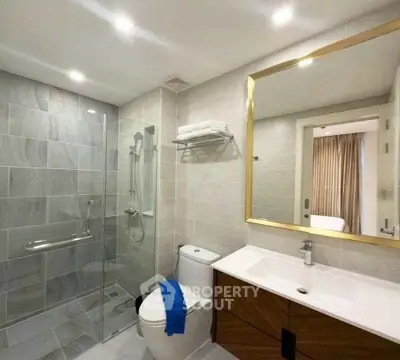Modern bathroom with glass shower, sleek vanity, and elegant lighting.