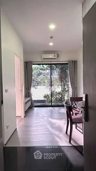 Modern living room with large window and garden view, featuring stylish dining area and air conditioning.
