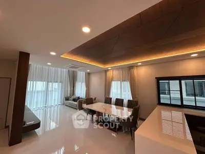 Spacious modern living room with elegant dining area and stylish ceiling design.