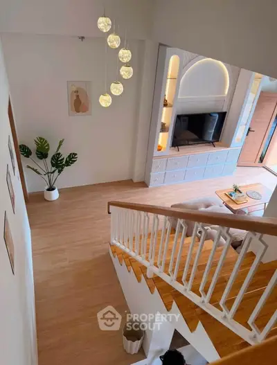 Modern living room with stylish staircase and elegant lighting, featuring cozy seating and decorative plants.