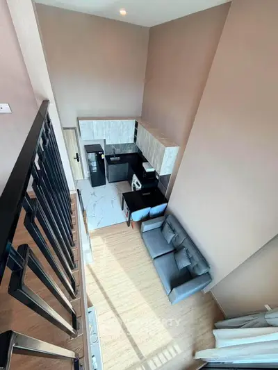 Modern loft apartment with open kitchen and cozy living area, featuring high ceilings and stylish design.