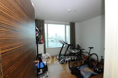 Spacious room with exercise equipment and stunning city view through large window.