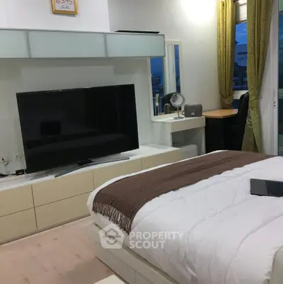 Modern bedroom with large TV and cozy decor in stylish apartment
