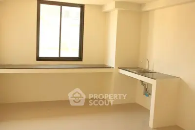 Minimalist kitchen space with large window and sleek countertop