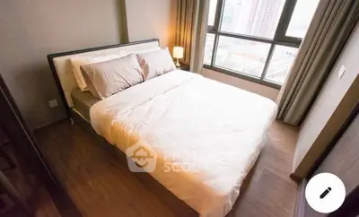 Cozy bedroom with large window and city view, featuring a comfortable double bed and warm lighting.