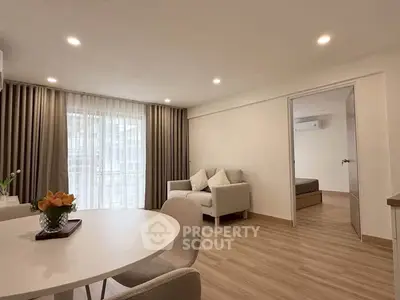 Modern living room with elegant decor and cozy seating, featuring a view into a stylish bedroom.